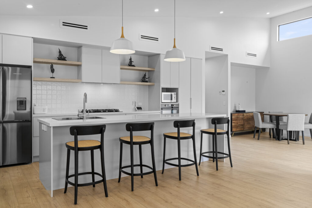 Renovated white kitchen with island bench and bar stools in a Sydney home by Daylo Build