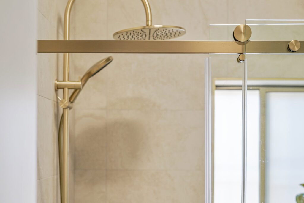Brushed brass rain shower and sliding glass screen in a West Ryde bathroom renovation