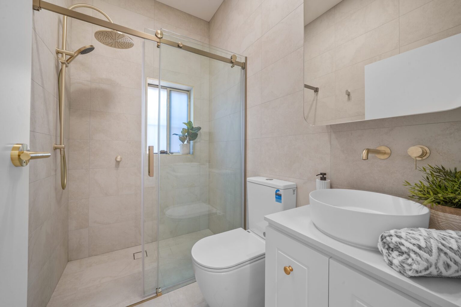 Renovated bathroom with brass shower fittings, glass screen and vanity in West Ryde by Daylo Build