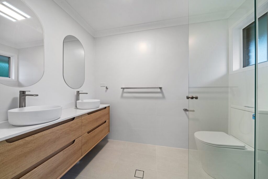 Renovated bathroom with walk-in shower, floating timber vanity and frameless glass in Lidcombe by Daylo Build