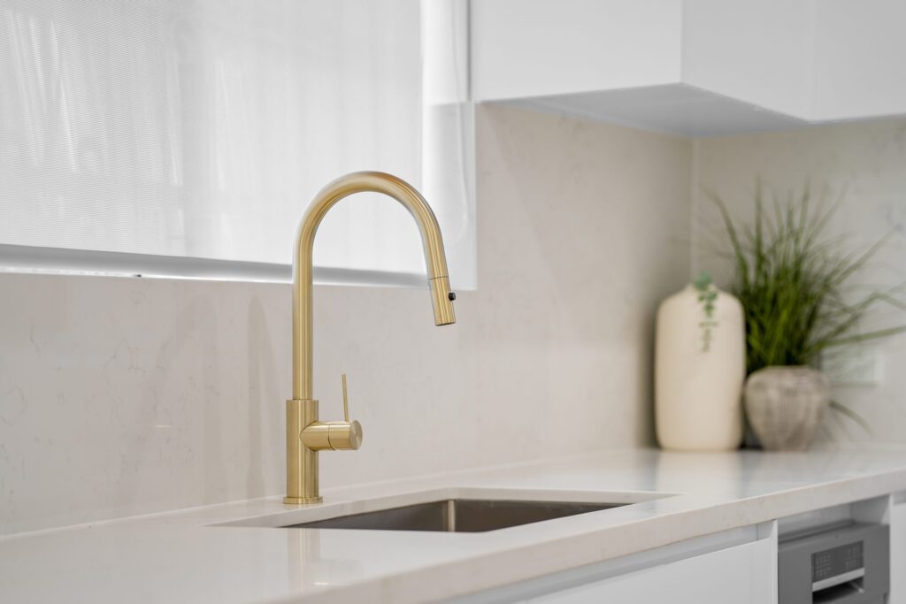 Kitchen with brass mixer tap, undermount sink and stone benchtop in a West Ryde renovation
