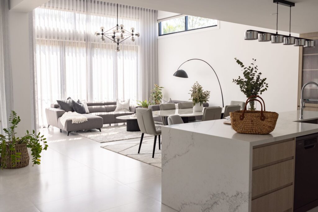 Open-plan living room and kitchen with stone waterfall island bench in a Box Hill home by Daylo Build