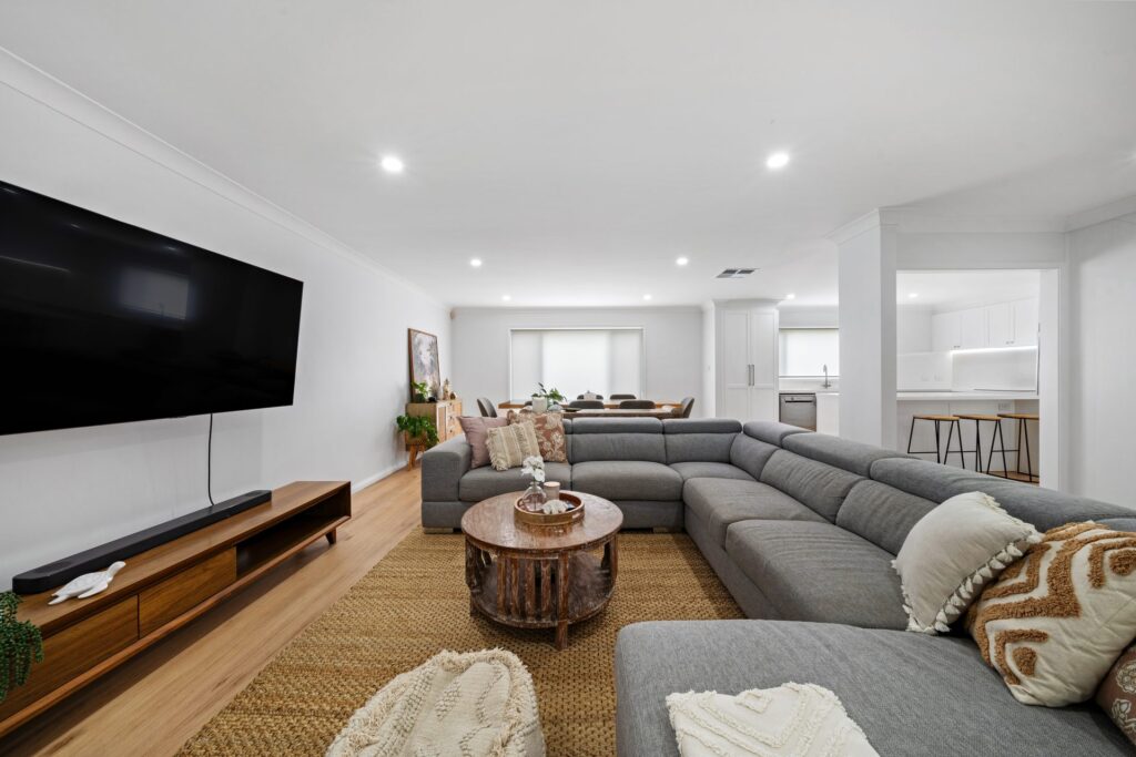 Renovated open-plan living room with timber flooring and built-in TV unit in Lidcombe by Daylo Build