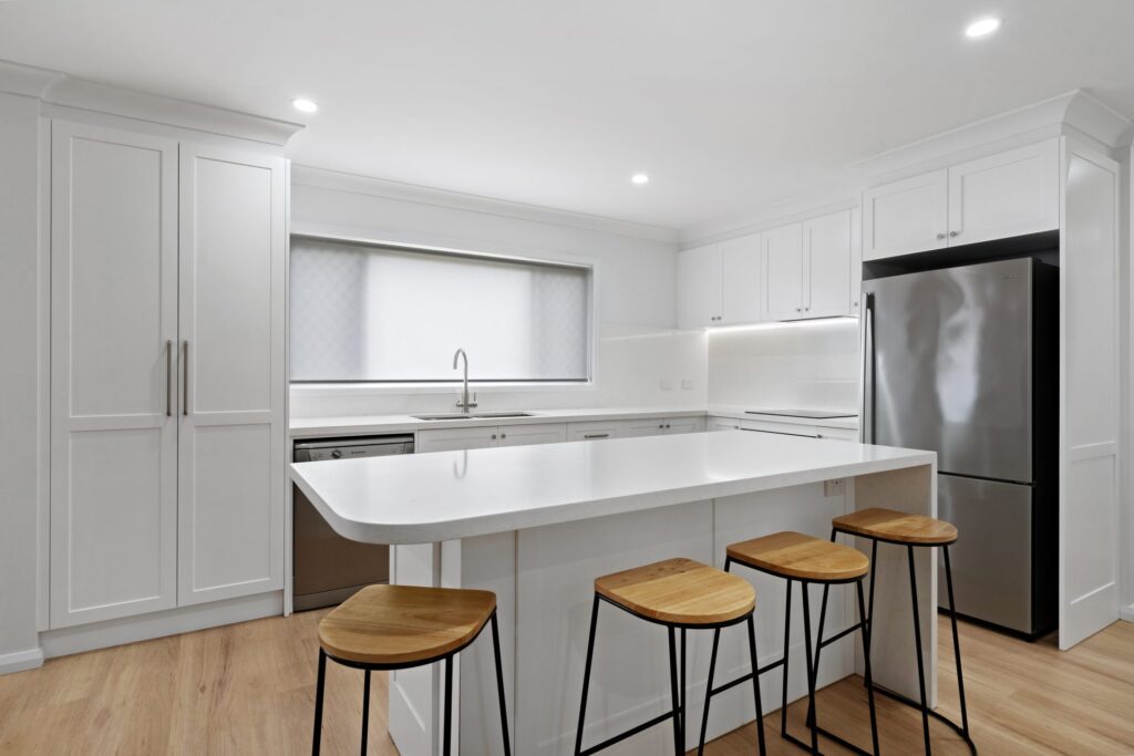 White shaker-style kitchen with island bench and bar stools in a Lidcombe home renovation by Daylo Build